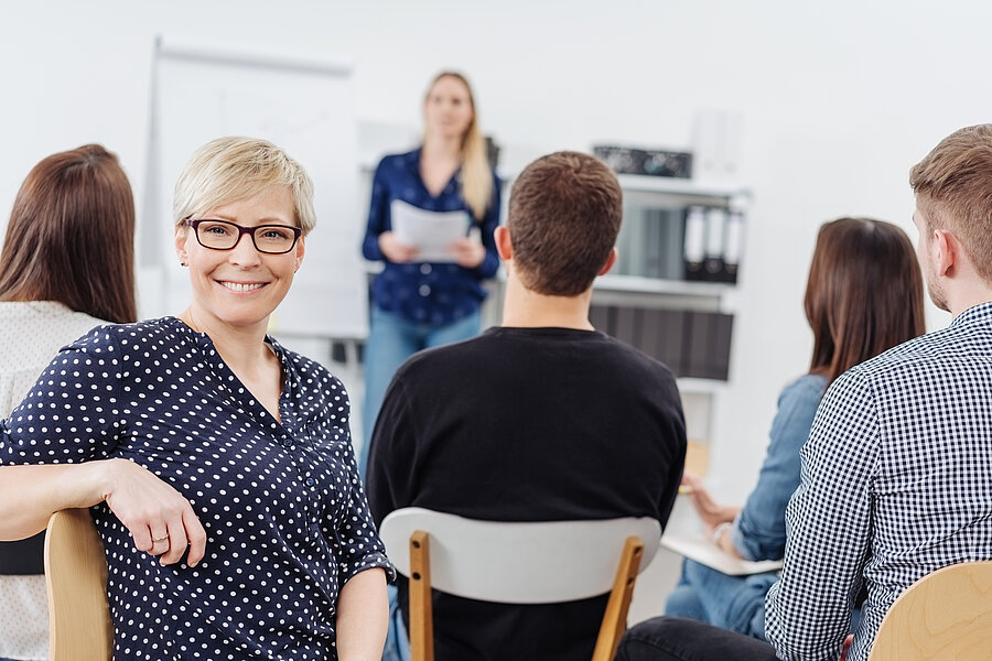 Woman smiling at camera during office meeting Woman smiling at camera during office meeting