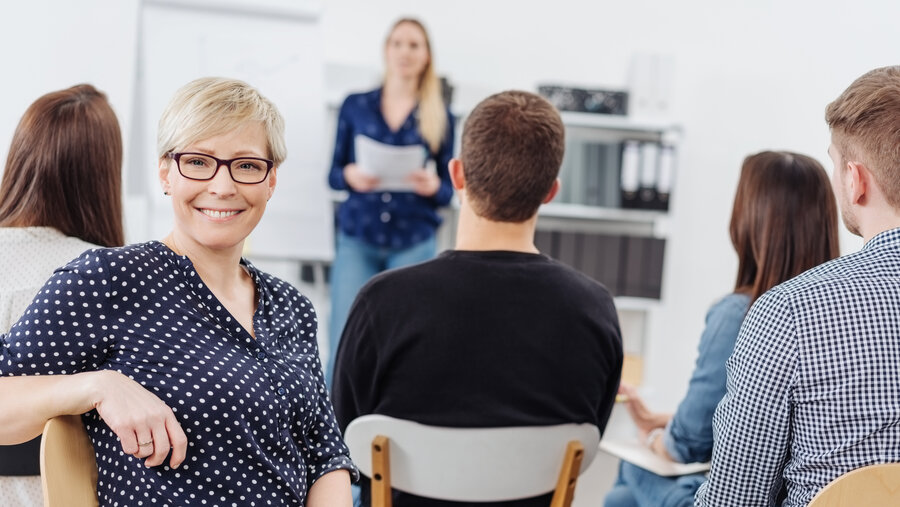 Woman smiling at camera during office meeting