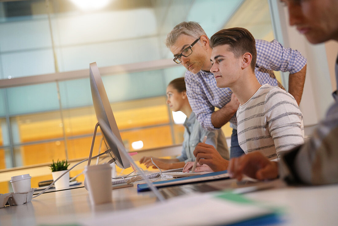 Teacher with students in apprenticeship attending computing class