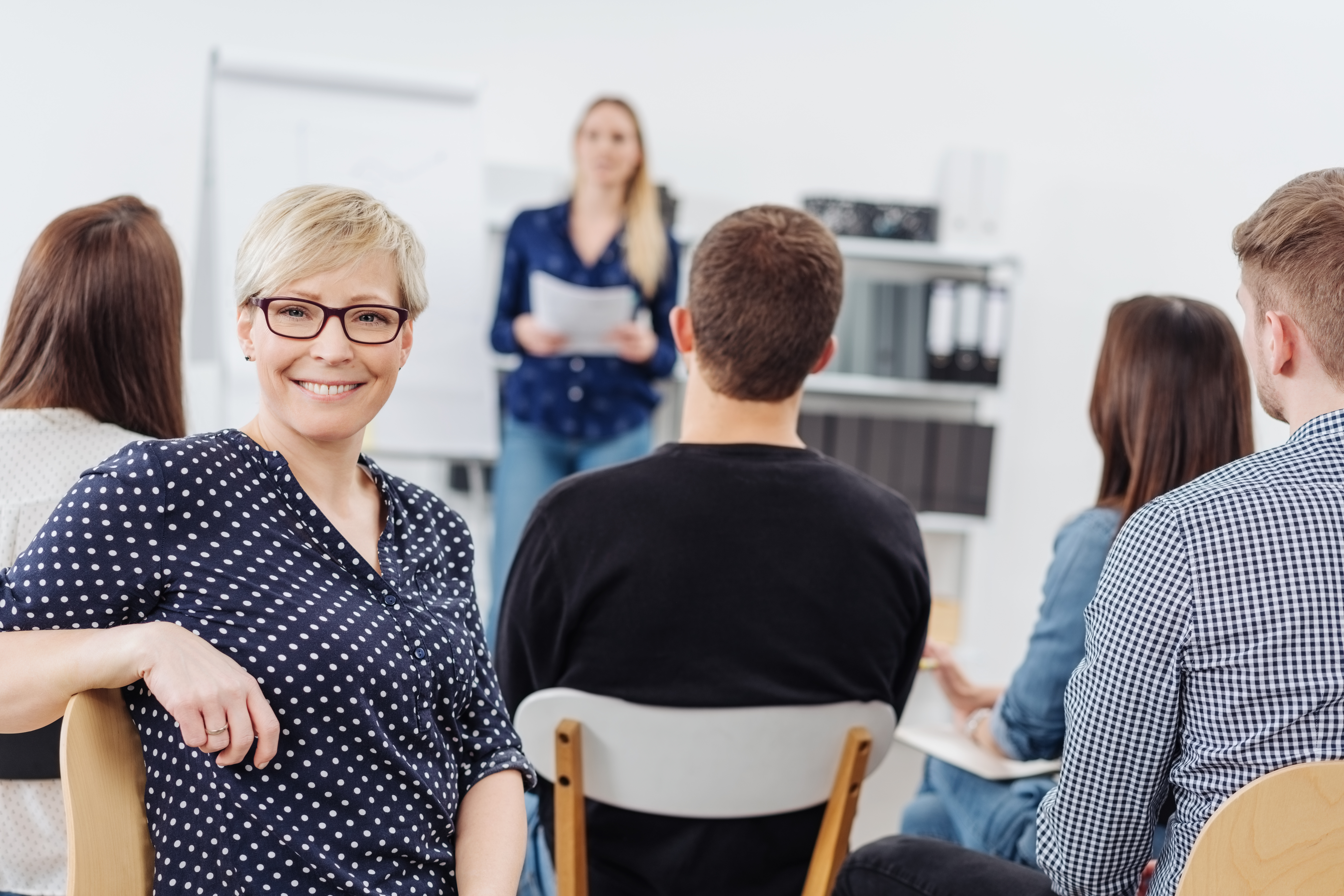 Woman smiling at camera during office meeting Woman smiling at camera during office meeting